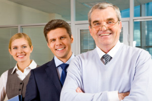 Image of senior leader smiling at camera with two employees behind