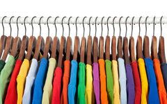 Variety of multicolored casual clothes on wooden hangers, on white background.